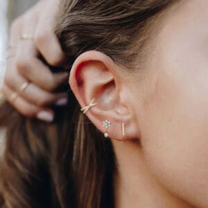 Woman wearing layered 18K gold stud earrings with multiple piercings lifestyle photography brown hair daily wear