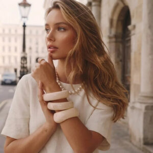 Woman wearing cream 18K gold sculpted bangle bracelet on wrist, vintage European street style, off-white thick rounded band jewelry