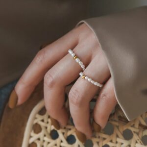 Stackable pearl rings with gold accents worn on hand - close-up detail view showing beaded design