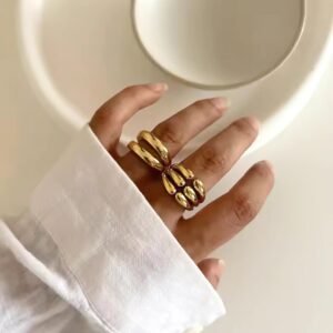 18k gold layered cuff ring worn on model hand close-up detail view minimalist styling white sleeve