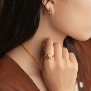 gold teardrop stacked rings stud earrings worn on female hand close-up portrait polished finish minimalist jewelry