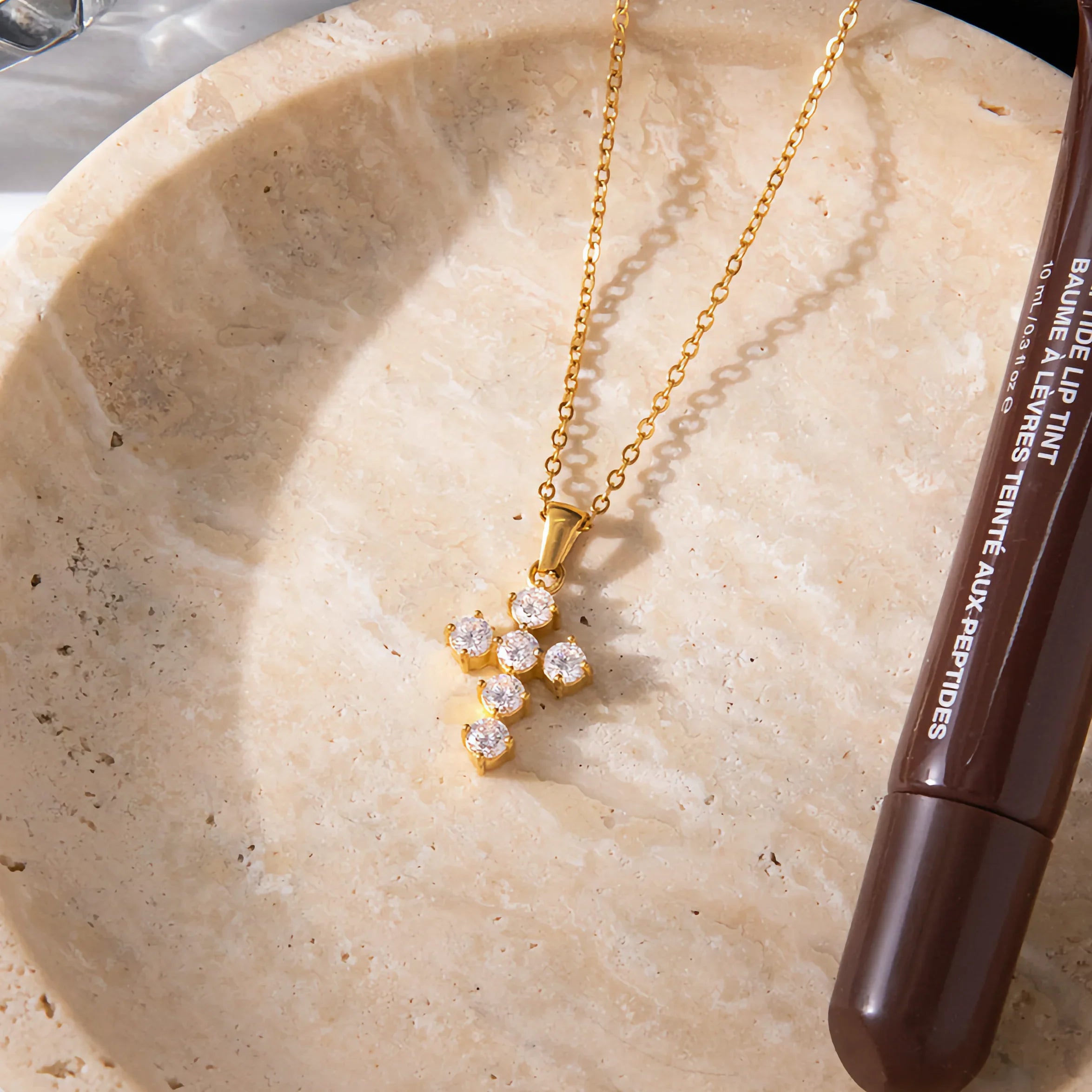 18k gold cross pendant with diamond simulants on marble surface overhead flat lay professional product photography