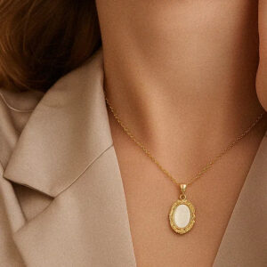 woman wearing 18k gold mother of pearl vintage pendant necklace close-up shot at collarbone with beige blazer elegant styling