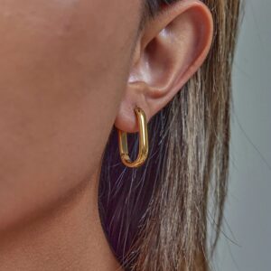 Delicate slim 14mm short gold hoop earrings worn on ear close-up showing minimalist design