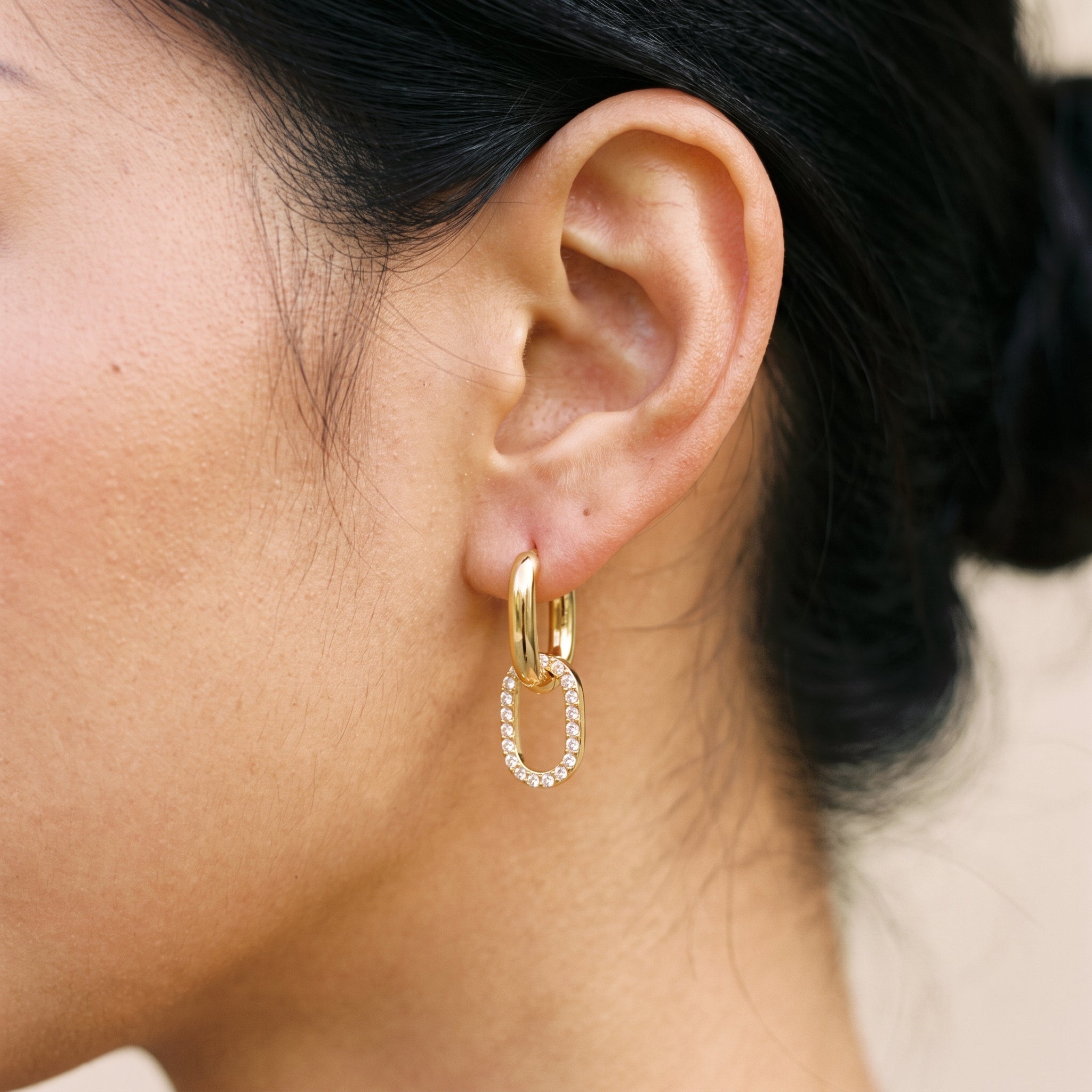 18K gold double hoop pavé diamond earrings earlobe close-up, interlocking oval hoops with crystal-paved band detail