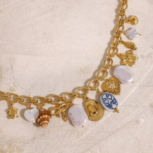 Close-up side view of baroque pearls and porcelain shell charms on 18K gold cable chain necklace