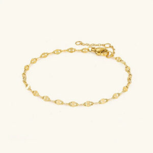 18K gold chain anklet flat lay overhead view showing delicate flat oval link chain design with secure lobster claw clasp on studio backdrop