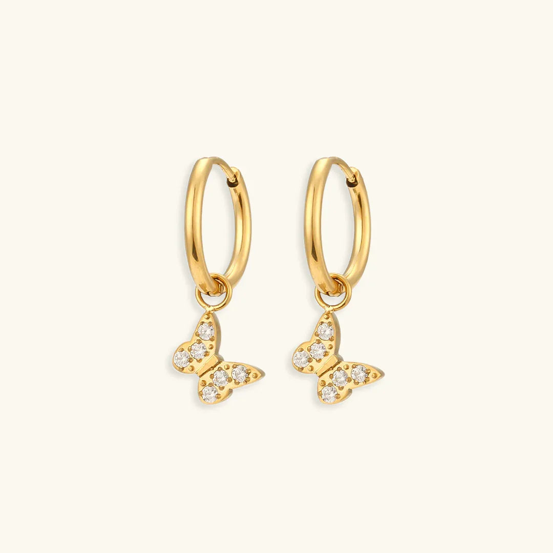 18K gold butterfly charm huggie hoop earrings with cubic zirconia pavé setting flat lay