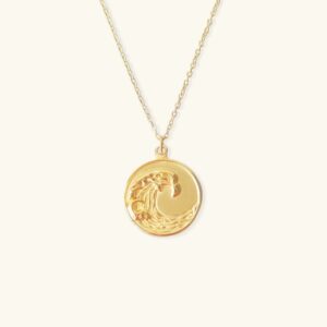18K gold wave pendant necklace featuring round coin medallion with embossed wave pattern and thin cable chain on white background