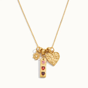 18K gold triple heart charm necklace with daisy flower pendant and triple heart bar with gemstone accents flat lay overhead product photography