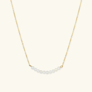 18K gold freshwater pearl necklace with curved pearl cluster on delicate gold chain, flat lay overhead view