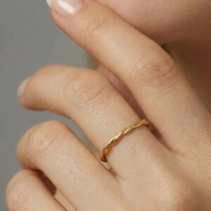 Close-up of 18K twisted gold band ring worn on finger, showcasing smooth polished finish and spiral texture detail