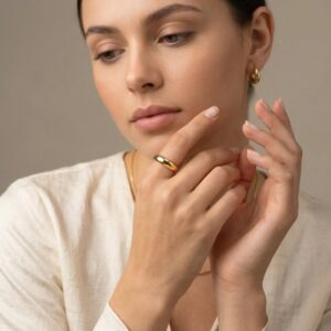 Delicate 18K gold minimalist ring worn on woman's right middle finger with cream linen styling everyday elegance