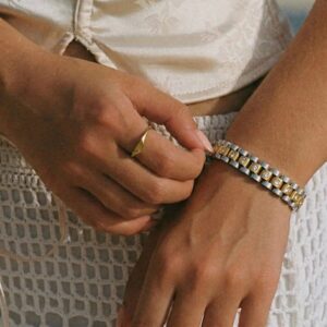 Close-up detail shot of 18K gold bracelet worn on model's wrist showing metal link texture and embedded rhinestone embellishments