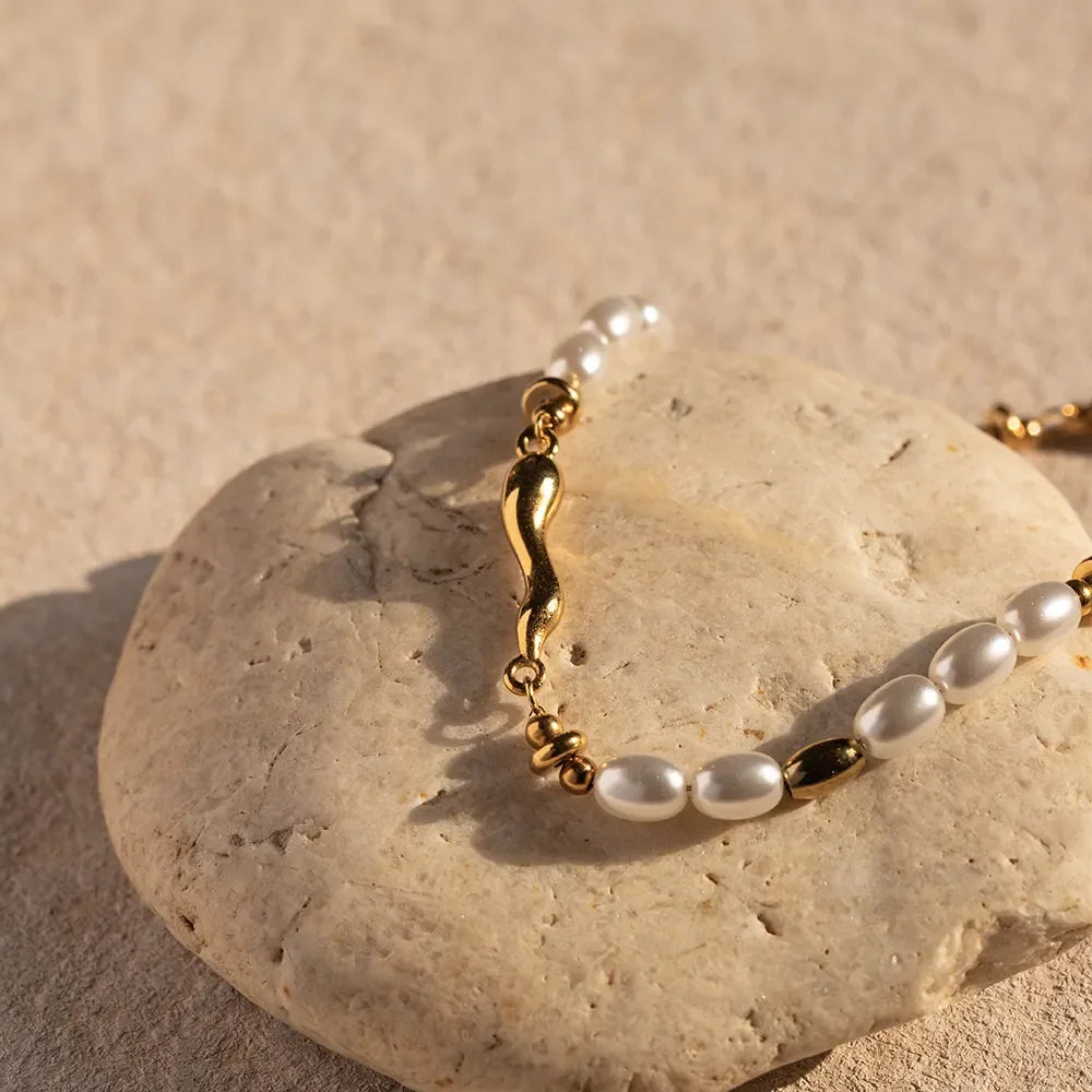 18K gold freshwater pearl bracelet flat lay on rough stone surface displaying complete bracelet structure and pearl spacing