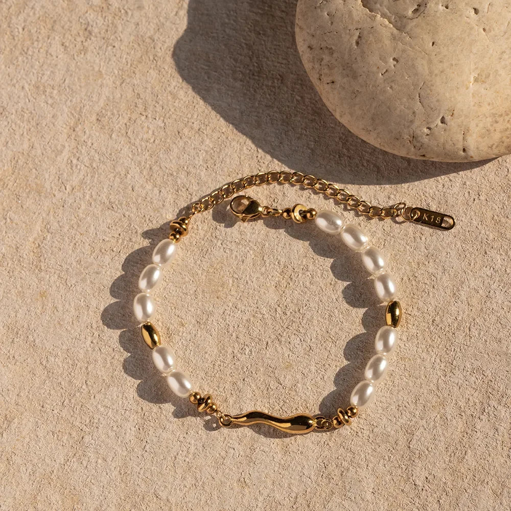 Luxurious 18K gold freshwater pearl bracelet displayed on textured stone surface with natural warm lighting and pearl details