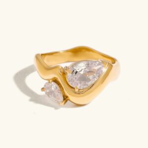 18K gold teardrop diamond ring with dual pear-cut stones on wavy band, flat lay overhead view