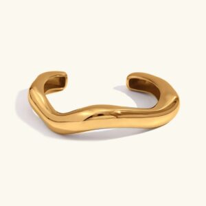 Asymmetrical 18K gold open cuff bangle with fluid wavy design, top-down flat lay view on plain background, polished finish