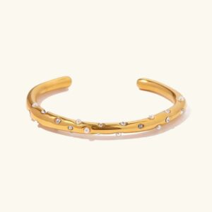 18K gold open cuff bangle with pearl and diamond simulant accents, polished finish, front flat lay on plain background