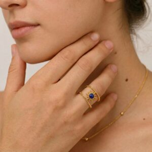 18K gold sun ring worn on female hands with gold necklace, close-up detail shot showing sun motif and blue stone, paired jewelry styling