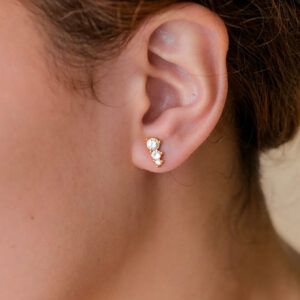 gold cluster stud earrings worn on woman's ear lobe close up portrait shot