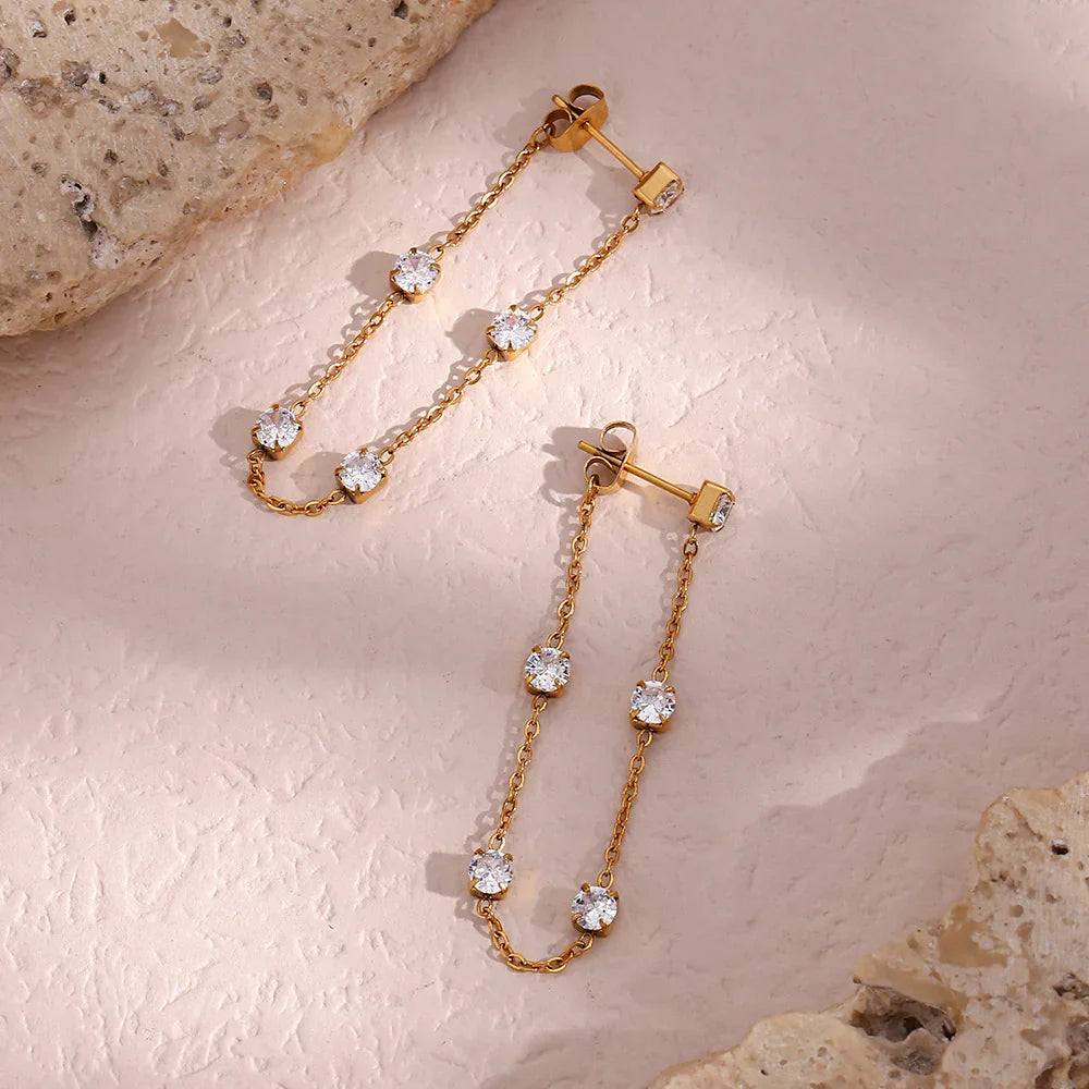 Overhead oblique view of 18K gold diamond simulant dangle earrings displaying round clear gems and geometric metal details