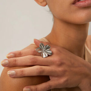 Hypoallergenic silver flower petal ring worn on female hand lifestyle shot index finger