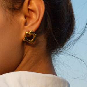 Woman wearing 18K gold heart earrings close up ear view hypoallergenic stud jewelry