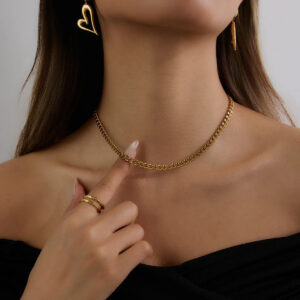 gold curb chain necklace worn on neck close-up black off-shoulder top delicate choker style