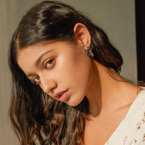 Woman wearing 18K gold teardrop earrings profile view long dark hair elegant metallic finish close-up model wearing jewelry