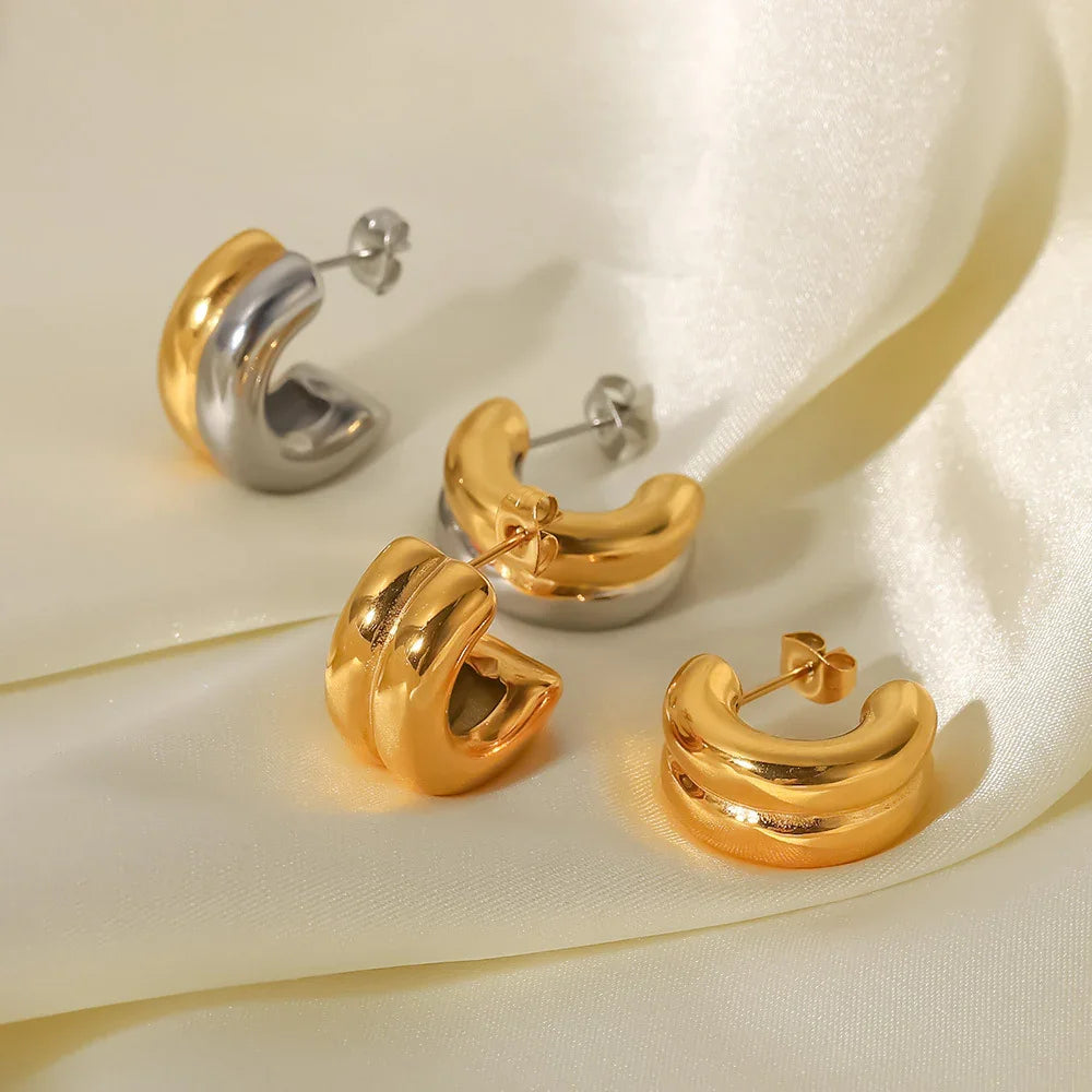 Mixed 18K gold and silver-gold two-tone chunky hoop earrings, oblique flat lay on ivory satin background