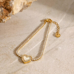 Adjustable 18K gold heart charm tennis bracelet with crystal-encrusted design and lobster clasp, top-down flat lay on marble backdrop