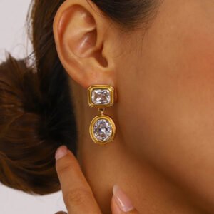 18K gold earrings worn on model ear, close-up side view showing dangling diamond pendant and secure post closure with natural styling