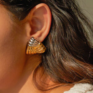 Two-tone mixed metal ridged stud earrings close-up on model's ear showing silver and gold finish twisted ridged geometric design