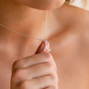 Personalized silver initial letter K pendant necklace worn on model neck, close-up fashion photography with delicate chain