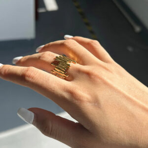 Worn 18K gold abstract ring on hand showing overlapping striped texture and wide band profile side view