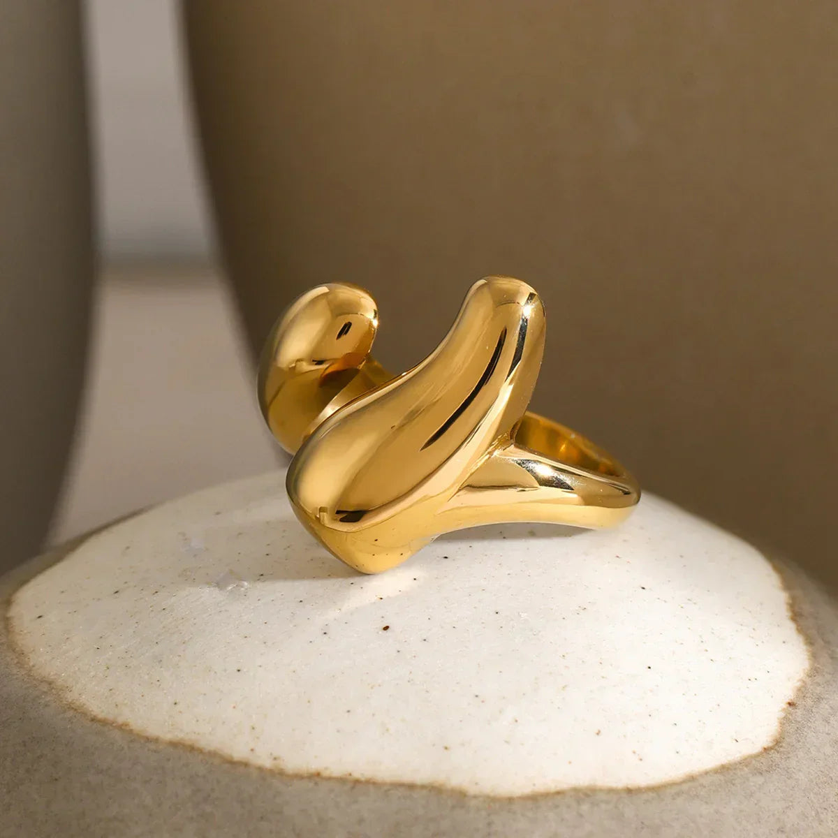 18K gold abstract double arc twisted ring design, smooth solid finish, front three-quarter perspective