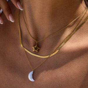 18k gold star and moon necklace worn on dark skin tone model showing stacked layered three-chain design with golden star and pearl crescent charms close-up neck view