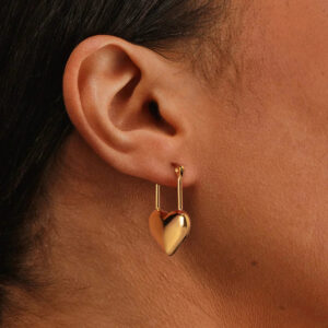 18K gold heart hoop earrings worn on ear light skin tone close-up showing dangling puffy heart charm and smooth warm gold color