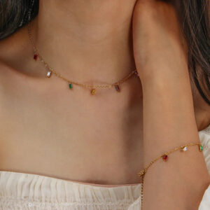 Slim gemstone choker and matching bracelet set worn by female model, close-up upper body view with multi-color stone charms