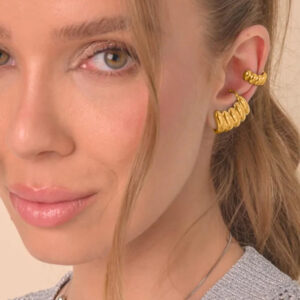 Female model wearing matching 18K gold ridged ear cuff and hoop earrings close-up side profile