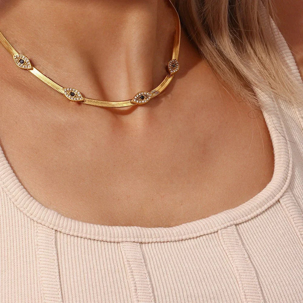 Evil eye herringbone gold choker necklace worn on model with square neck ribbed knit top showcasing front neck close-up