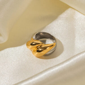 Two-tone twisted heart ring side oblique view showing gold heart detail and silver band sleek polished surface