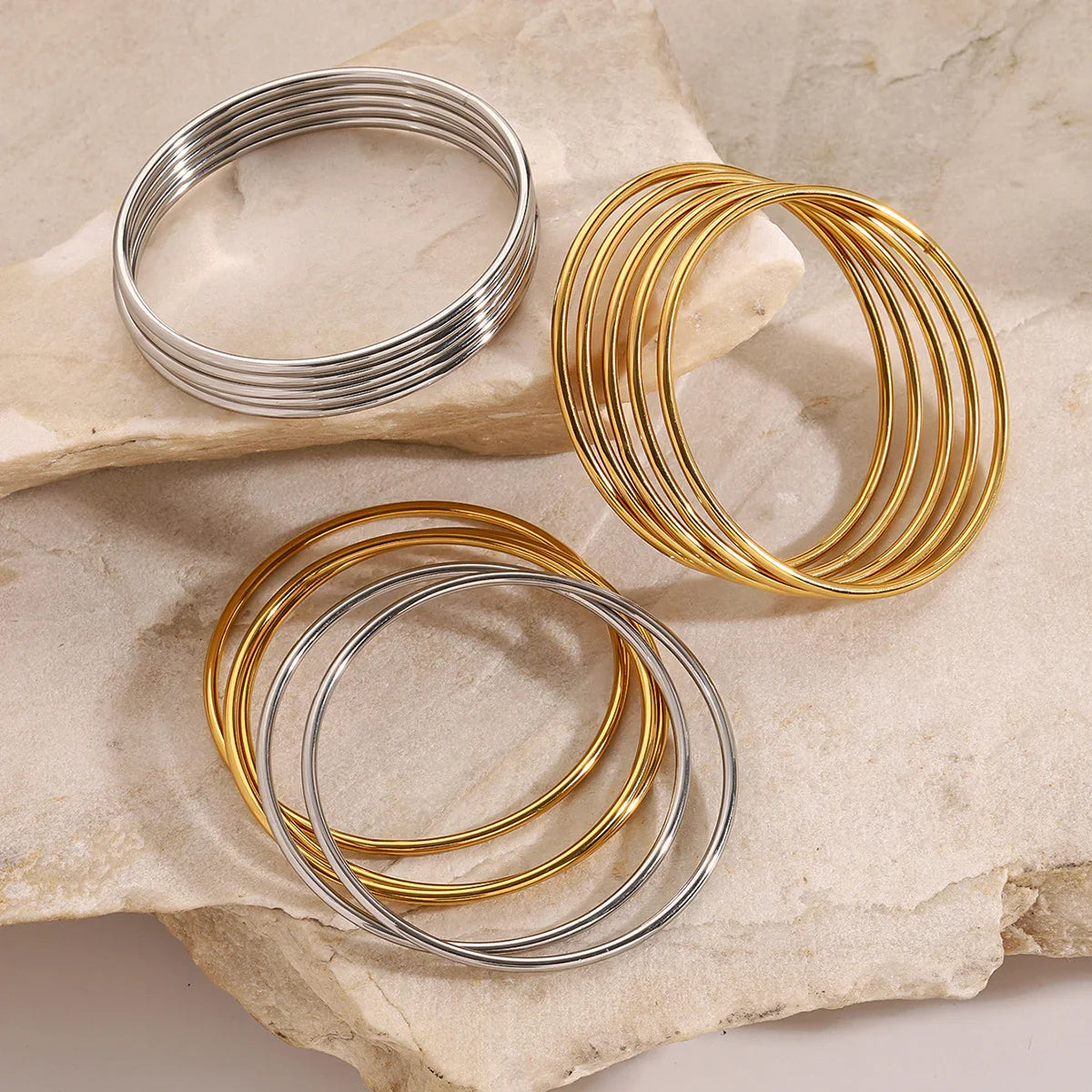 Mixed gold and silver slim bangles arranged on neutral background - versatile styling