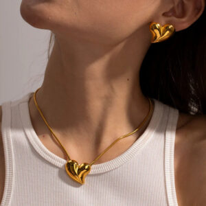 gold heart jewelry set worn on model neck and ear close-up shot showing matching stud earrings