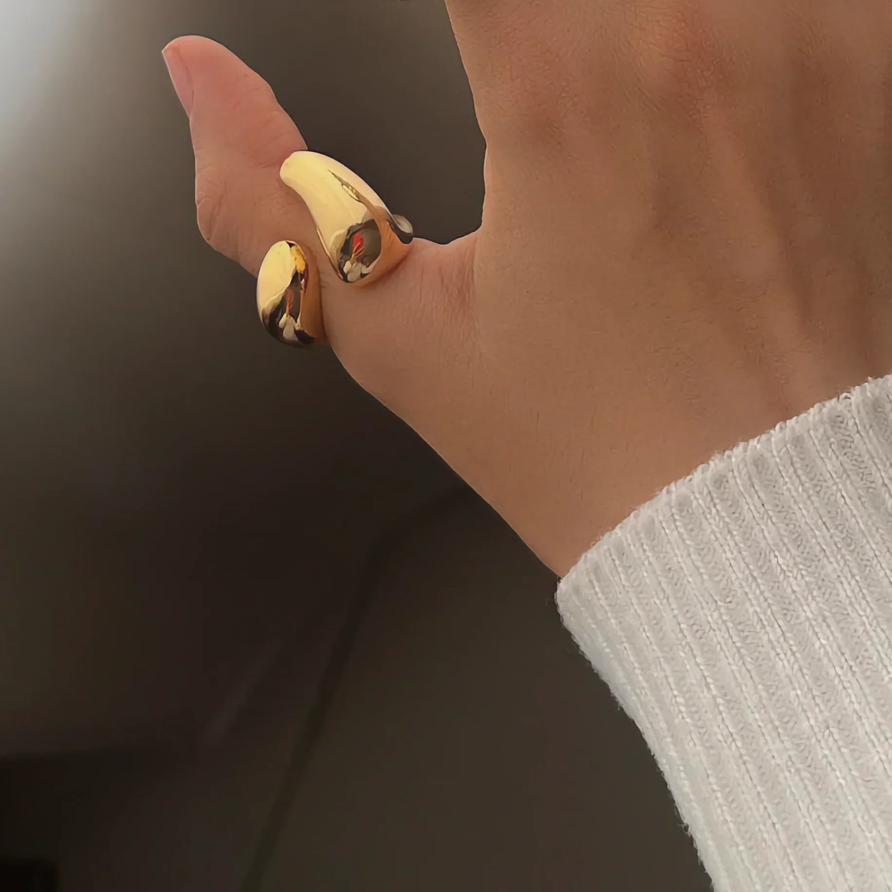 18K gold abstract cuff ring worn on hand, showing wrap-around open band design in close-up side view