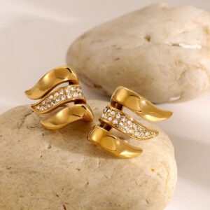 18K gold wave earrings oblique top-down shot displaying crystal inlay and polished metal details with warm desktop lighting