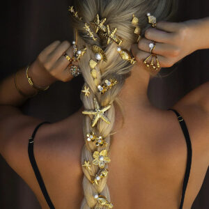 Gold marine hair clip styled in blonde braided hair back view wearing black top