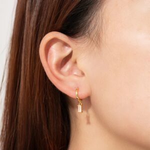 Side profile close-up of 18K gold huggie earrings worn on female ear highlighting dainty design and elegant fit