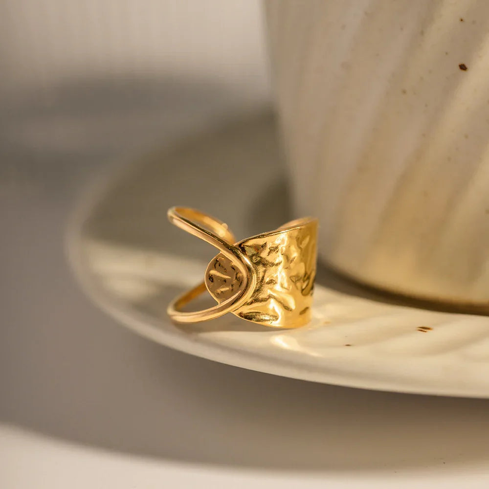 Polished 18K gold irregular wrap ring side oblique view with table dining scene